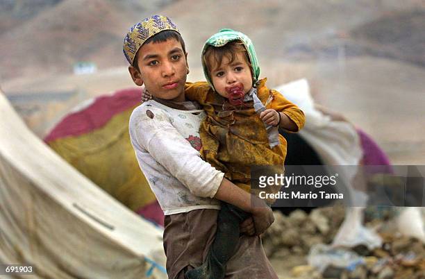 Afghan refugee Abdullah carries his sister Babi January 9, 2002 outside Kandahar, Afghanistan. Abdullahs family has been living in a tent near the...