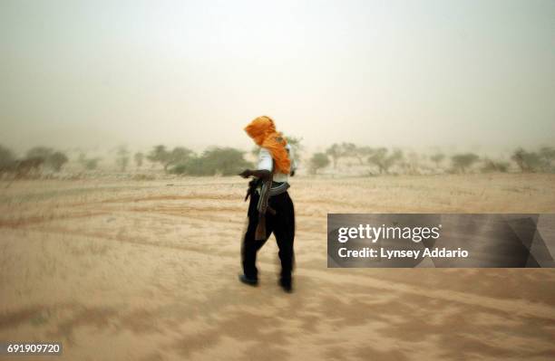 Soldier with the Sudanese Liberation Army walks through a sandstorm in the village of Shigekaro, in Darfur, August 22, 2004. The SlA is one of the...