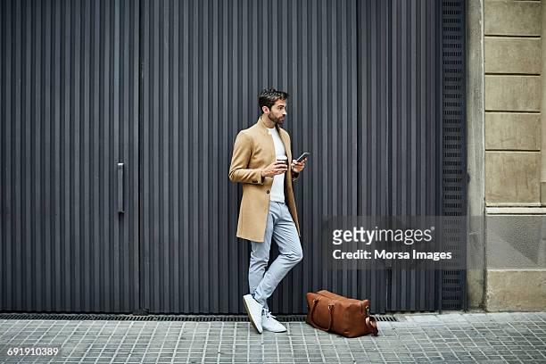 businessman with phone and cup looking away - business man texting stock-fotos und bilder