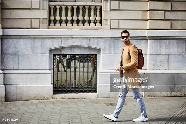 businessman walking on sidewalk by building - brown jacket foto e immagini stock