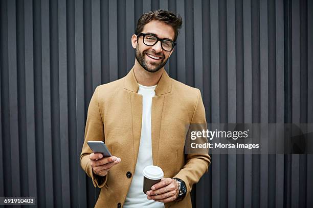 happy businessman with smart phone and cup in city - barbe de 3 jours photos et images de collection