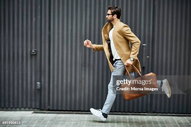 businessman with bag running on sidewalk in city - hustle ストックフォトと画像