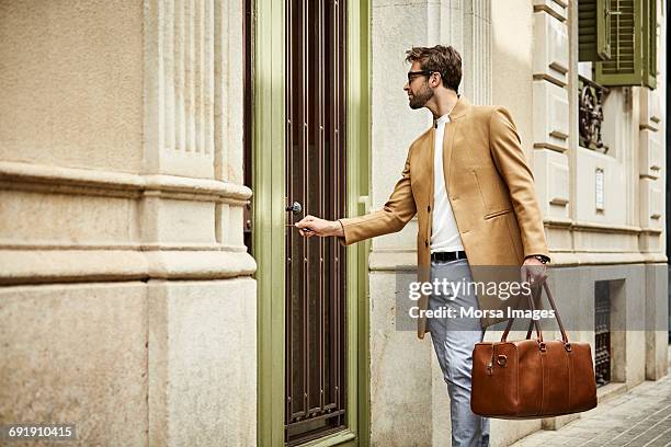 businessman locking door at sidewalk in city - entrance building people stock-fotos und bilder