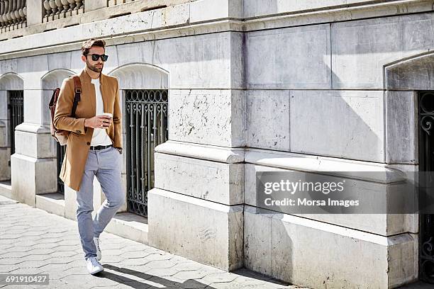 businessman holding cup with hand in pocket - fashionable men stock pictures, royalty-free photos & images