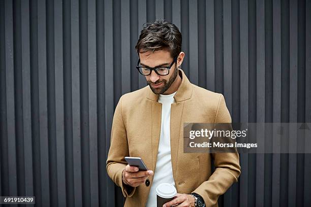 businessman using phone and holding cup in city - look down - fotografias e filmes do acervo