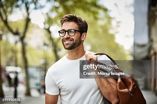 Smiling businessman with brown bag walking in city Smiling businessman with brown bag walking in city