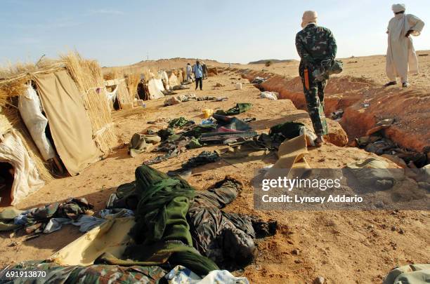 Sudanese rebels with the NRF walk past dead Sudanese government soldiers as they walk through a temporary military camp for the GOS near the Darfur...