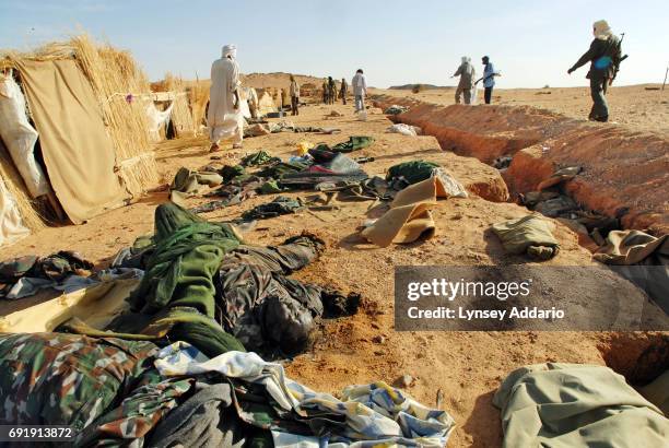 Sudanese rebels with the NRF walk past dead Sudanese government soldiers as they walk through a temporary military camp for the GOS near the Darfur...