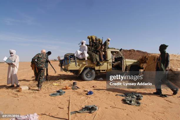 Sudanese rebels with the NRF pick up ammunition and weapons left behind from defeated GOS soldiers as the rebels walk through a temporary military...
