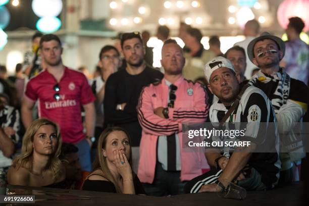 Football fans watch a large screen showing the UEFA Champions League final football match between Juventus and Real Madrid in the 'Depot' bar in...