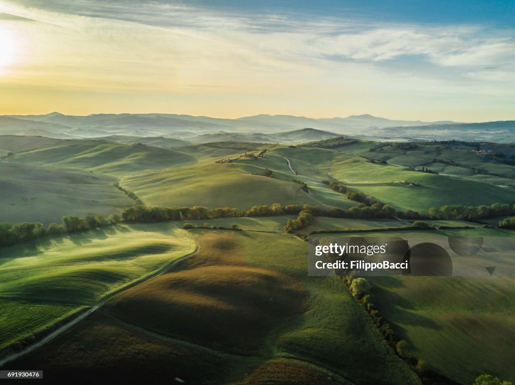 Tuscany landscape at sunrise with low fog