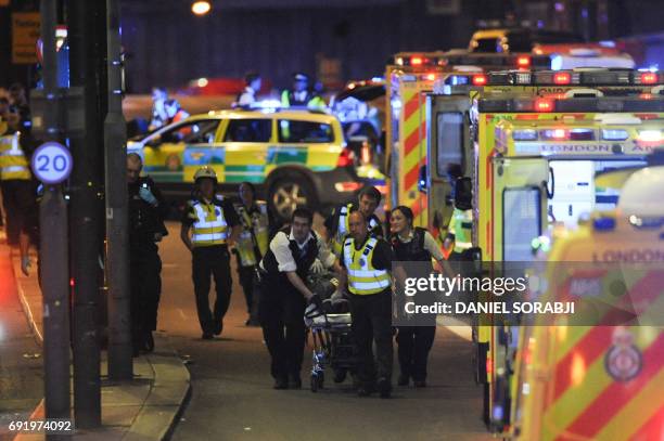 Police officers and members of the emergency services attend to a person injured in an apparent terror attack on London Bridge in central London on...