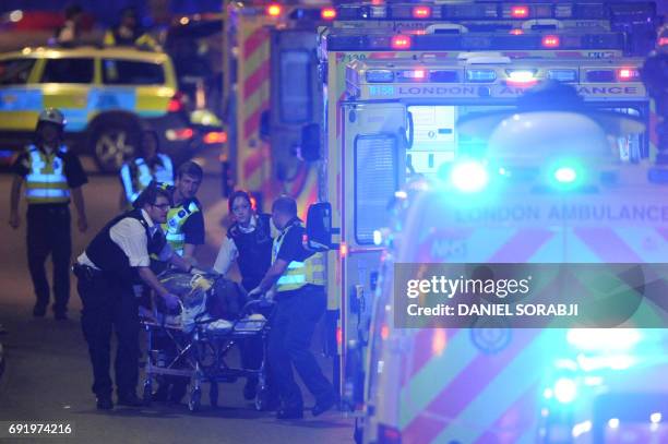 Police officers and members of the emergency services attend to a person injured in an apparent terror attack on London Bridge in central London on...