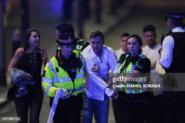 Police escort a member of public as they clear the scene of a terror attack on London Bridge in central London on June 3, 2017. Armed police opened...