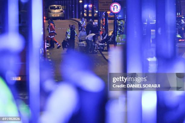 Police and members of the emergency services attend to victims of a terror attack on London Bridge in central London on June 3, 2017. Armed police...