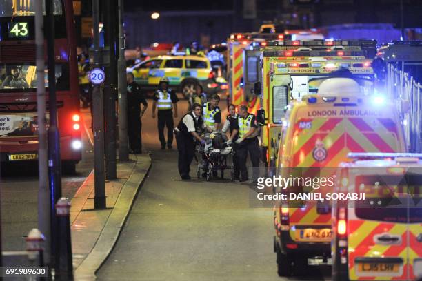 Police officers and members of the emergency services attend to a person injured in an apparent terror attack on London Bridge in central London on...