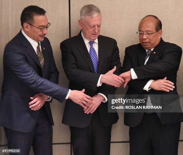 Pentagon chief Jim Mattis reaches for hand shakes with Malaysian Defence Minister Hishammuddin Tun Hussein and U Thaung Tun , National Security...