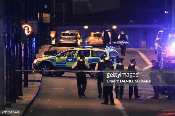 Police officers walk at the scene of an apparent terror attack on London Bridge in central London on June 3, 2017. Armed police fired shots after...