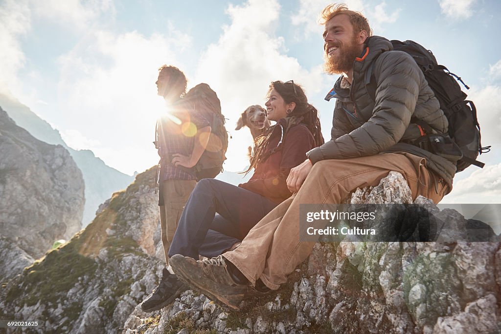 Three friends witting with dog on mountain top, Innsbruck, Tyrol, Austria