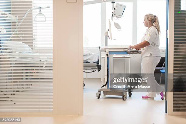 nurse on hospital ward pushing trolley - netherlands stock-fotos und bilder
