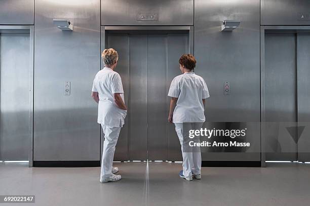 rear view of nurses in hospital waiting for elevator - hospital elevator stock pictures, royalty-free photos & images