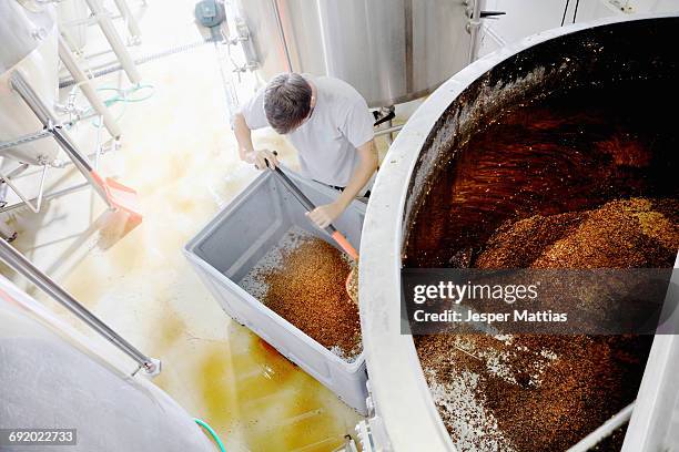 worker emptying spent grains from mash tun, overhead view - craft brewery stock pictures, royalty-free photos & images