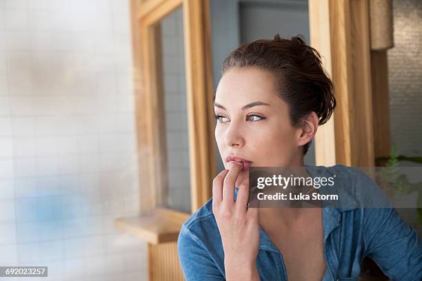 young woman with thoughtful expression - kauen stock-fotos und bilder