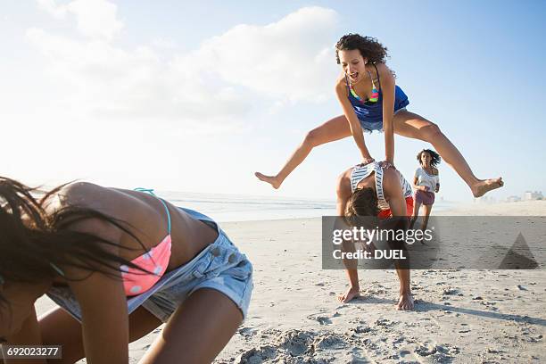 young man and three female friends playing leapfrog on beach, cape town, south africa - 2015 18 stock pictures, royalty-free photos & images