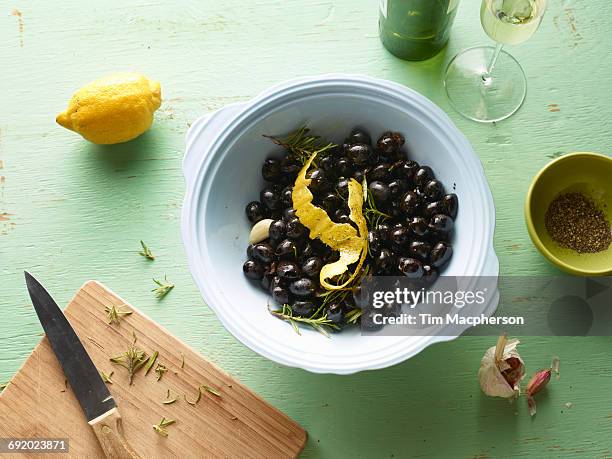 overhead view of bowl of black olives with lemon peel on table - halstock stock-fotos und bilder