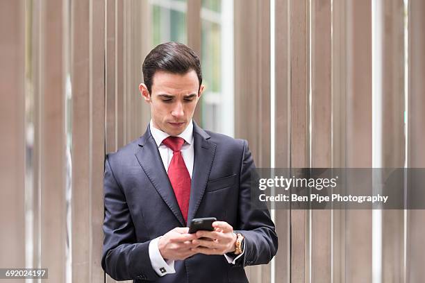 businessman in city looking at smartphone - red tie stock pictures, royalty-free photos & images