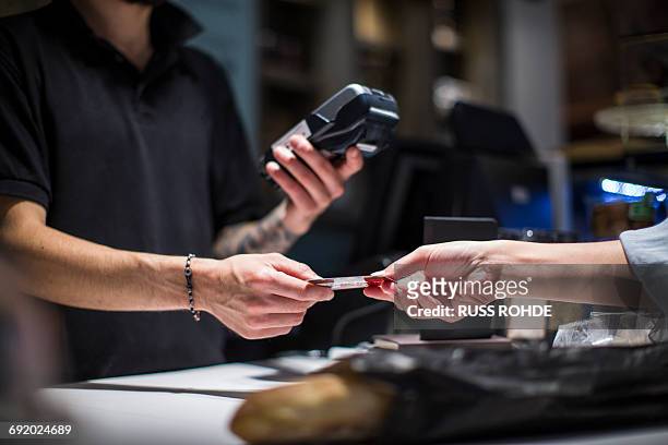 close up of barista handing credit card to female customer - man offering bread stock pictures, royalty-free photos & images