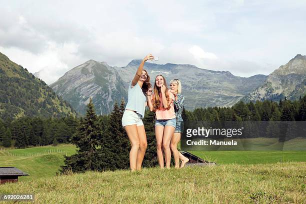 three adult female friends taking smartphone selfie in austrian alps, sattelbergalm, tirol, austria - österreichische zentralalpen stock-fotos und bilder