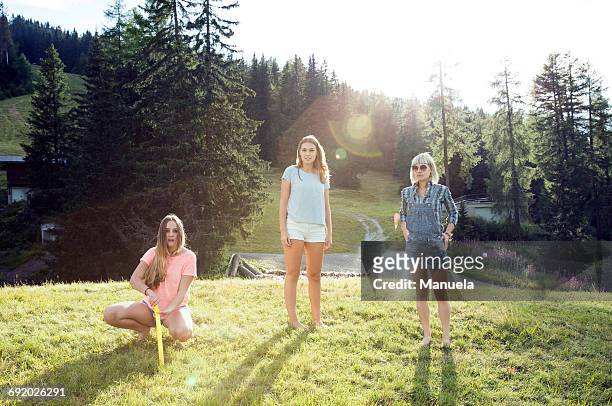 portrait of three adult female friends standing and crouching in field, sattelbergalm, tirol, austria - tirol deelstaat stockfoto's en -beelden
