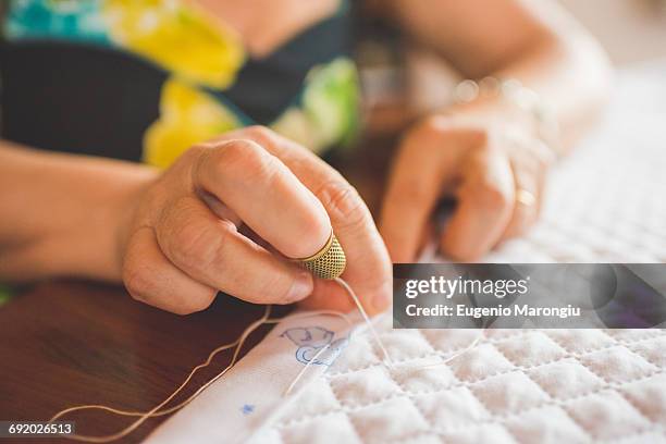 cropped view of woman sewing hem on quilt - hem foto e immagini stock