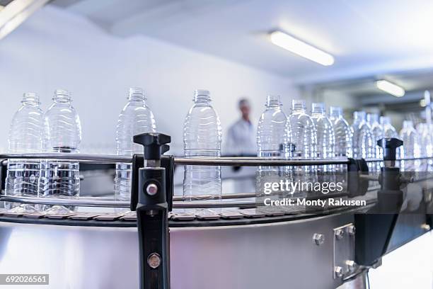 newly-manufactured plastic bottles on production line in spring water factory - bottle factory stockfoto's en -beelden