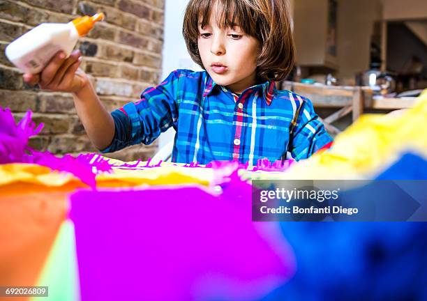 boy spreading glue on crepe paper to make pinata - crepe paper stock pictures, royalty-free photos & images