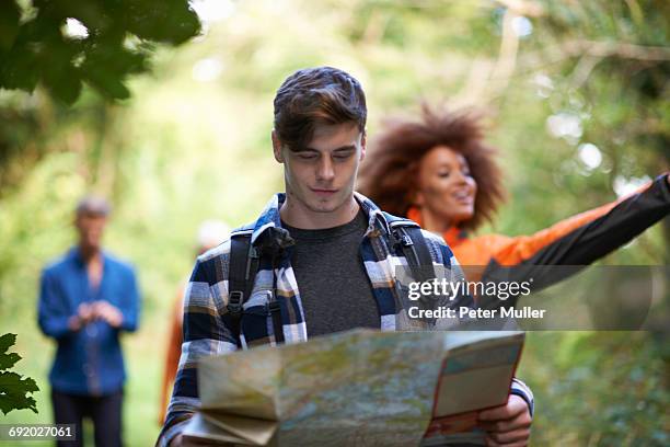 man hiking with friends in forest looking at map - orientierungslauf landkarte gruppe stock-fotos und bilder