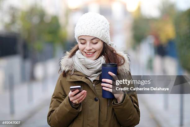 a young woman with a smartphone in the street - winter coats stockfoto's en -beelden