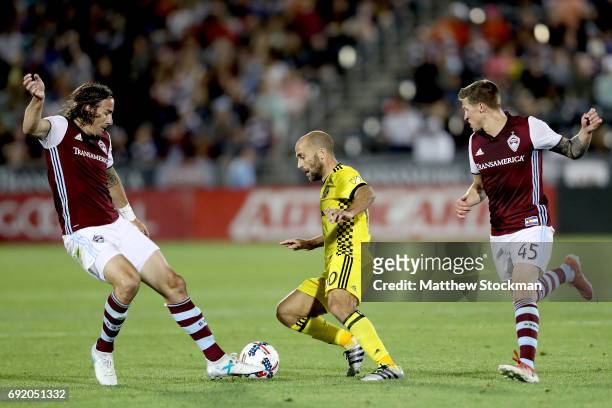 Alan Gordon @16 and Joshua Gatt of the Colorado Rapids try to contain Federico Higuain of Columbus Crew SC at Dick's Sporting Goods Park on June 3,...