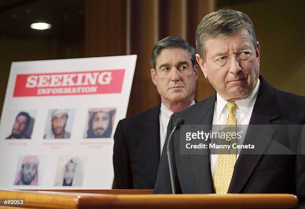Attorney General John Ashcroft and FBI Director Robert Mueller watch a video of suspected al Qaeda terrorists during a press conference January 17,...