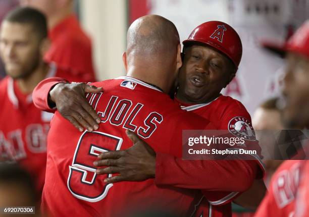 Albert Pujols of the Los Angeles Angels of Anaheim is hugged by first base coach Alfredo Griffin after Pujols' career home run number 600, a grand...