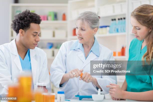 group of pharmacists fill customers prescription orders - african mortar and pestle stock pictures, royalty-free photos & images