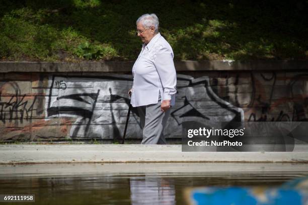 An elderly woman with a crutch is seen in a park in the center of Bydgoszcz, Poland on 3 June, 2017.