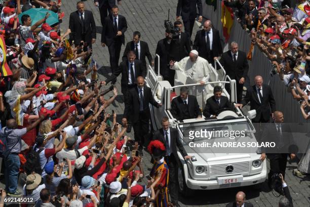 Pope Francis stands on the popemobile surrounded by bodyguards as he greets the crowd after a Pentecost mass on June 4, 2017 at St Peter's square in...