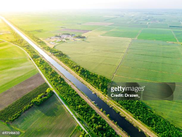 danube canal stretches between agricultural plots and farms - canal stock pictures, royalty-free photos & images