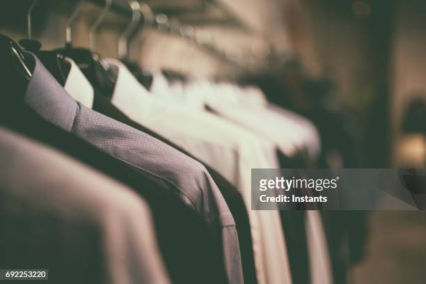 close-up shot of blue blouses with coathangers on a clothes rack. - menswear stock pictures, royalty-free photos & images