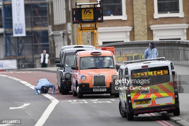 Forensic officer checks under a taxi as they work on London Bridge following last night's terrorist attack on June 4, 2017 in London, England. Police...