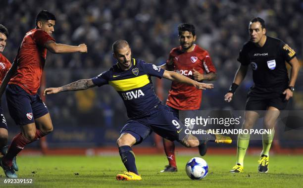 Boca Juniors' forward Dario Benedetto , between Independiente's defender Alan Franco and midfielder Walter Erviti , kicks to score the team's third...