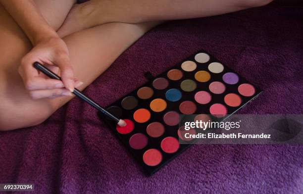 woman holding a makeup brush over an eyeshadow palette. - viollet creative selects stock pictures, royalty-free photos & images