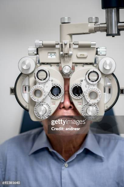 adult patient getting an eye exam at the optician - phoropter stock pictures, royalty-free photos & images